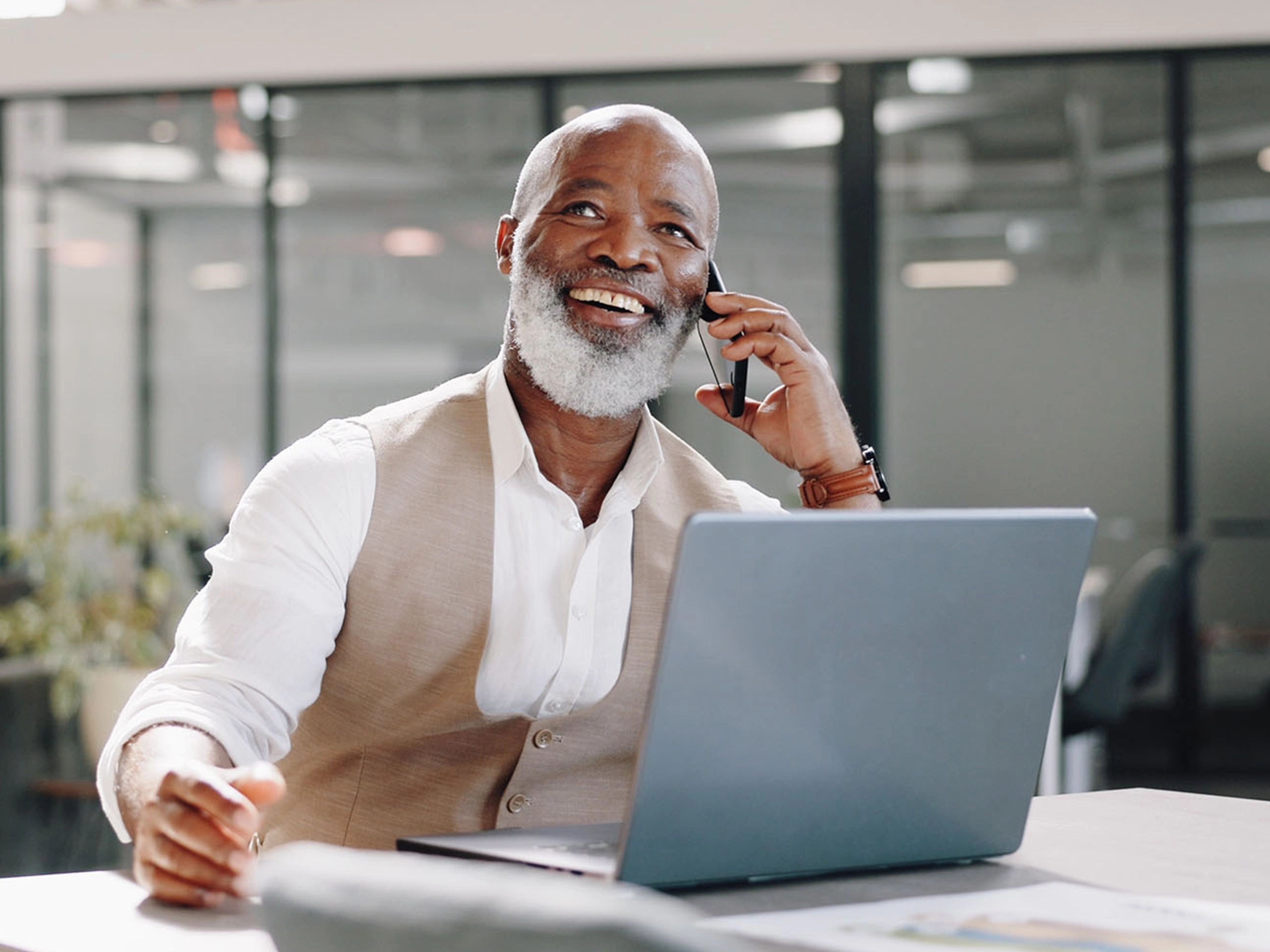 Smile, phone call or happy senior businessman in office for networking, good news or deal negotiation. Black man, laptop or mature CEO on mobile communication for target, discussion or sales mission